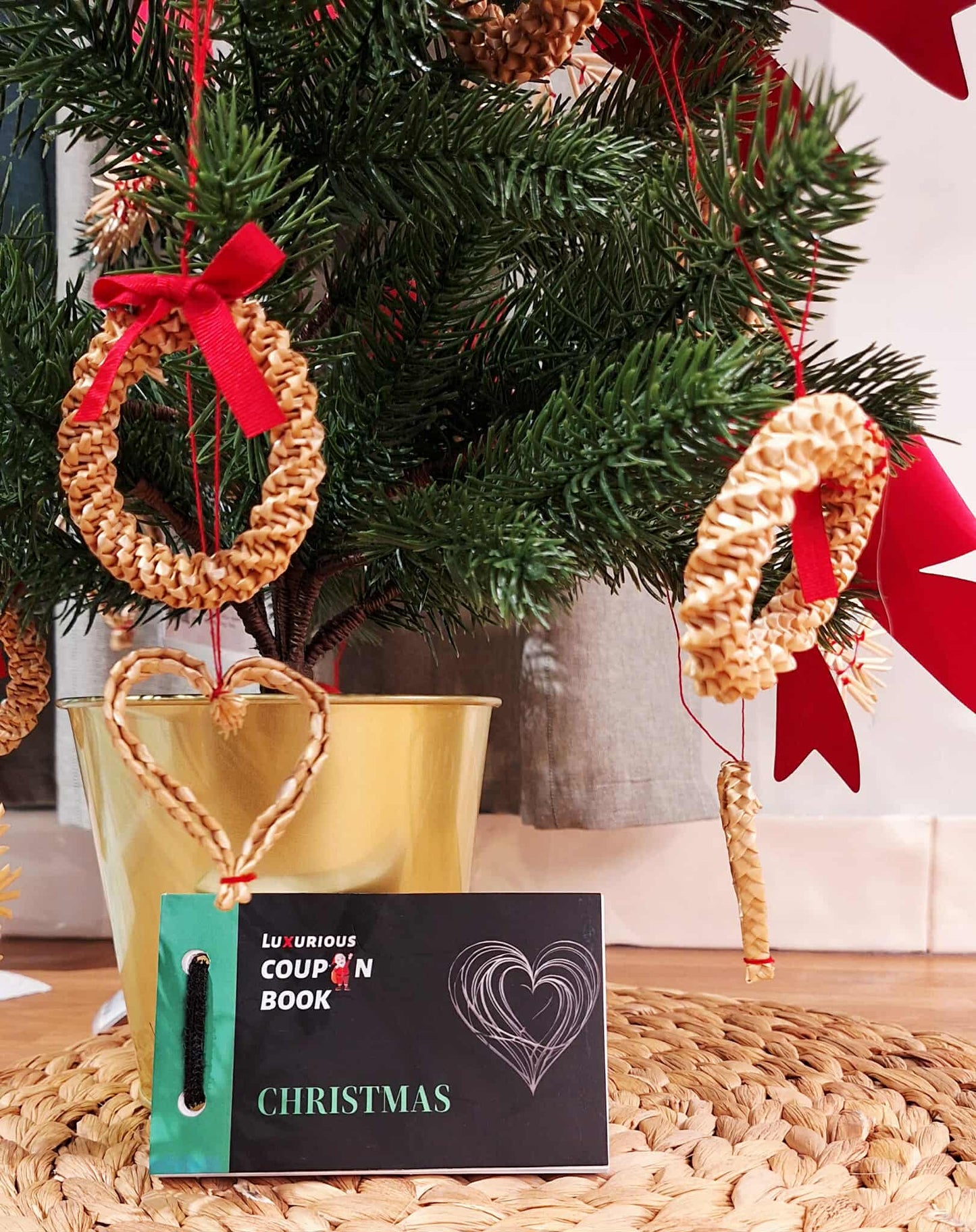 Decorative Christmas tree with woven heart and wreath ornaments and a coupon book.